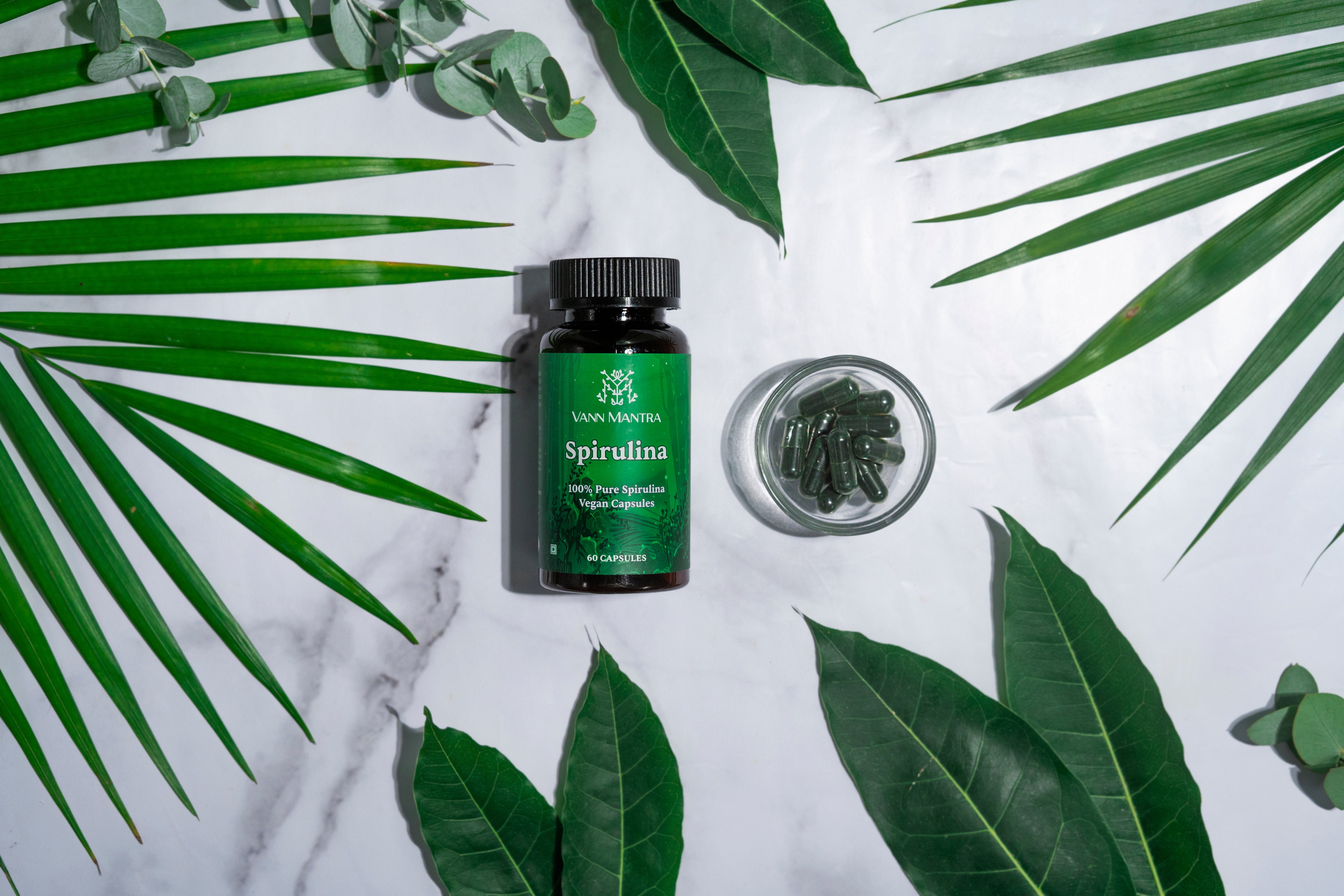 Spirulina Capsules on a backdrop with plants.