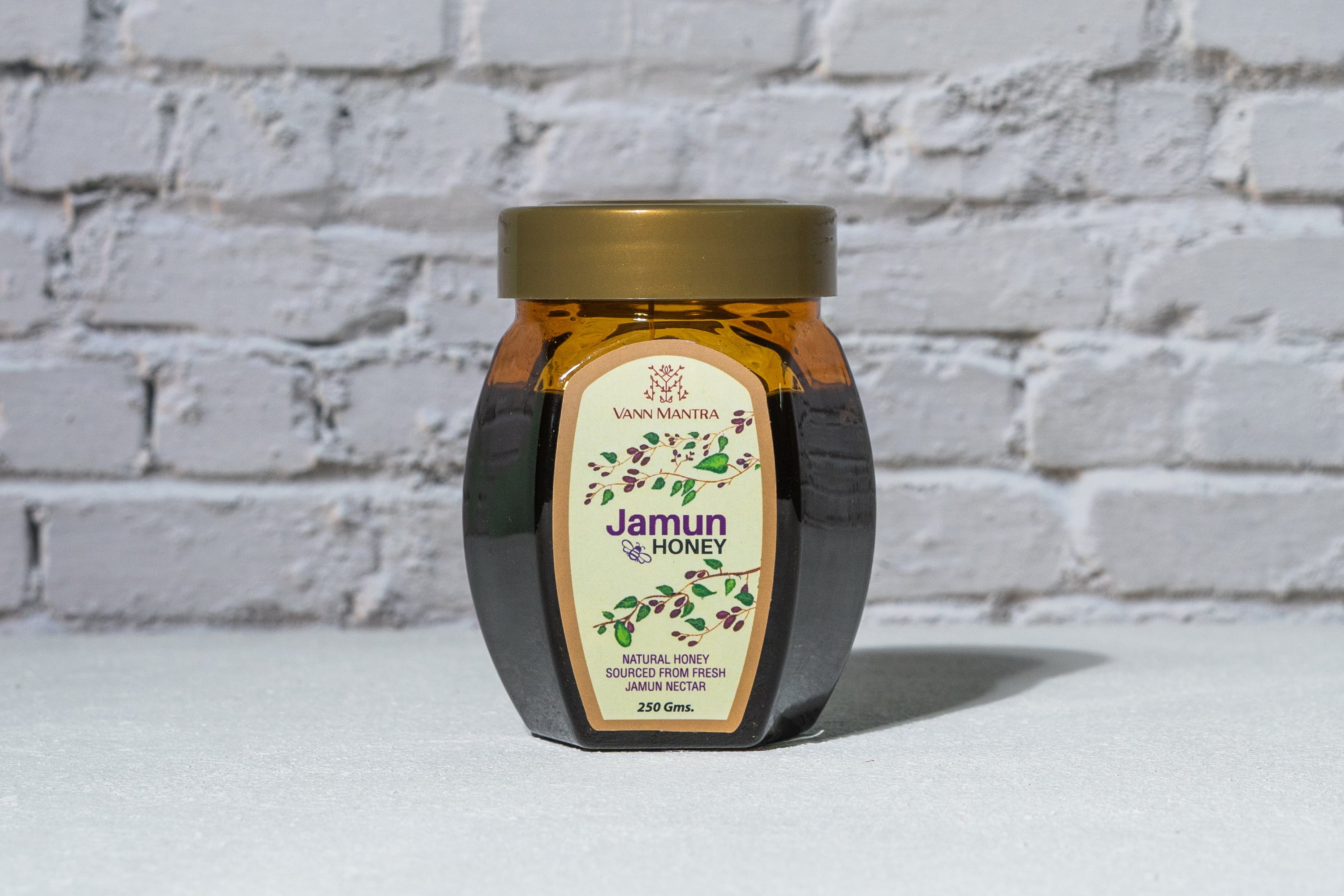 Jar of Jamun Honey in front of a brick wall 