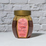 Jar of Lychee Honey in front of a brick wall 