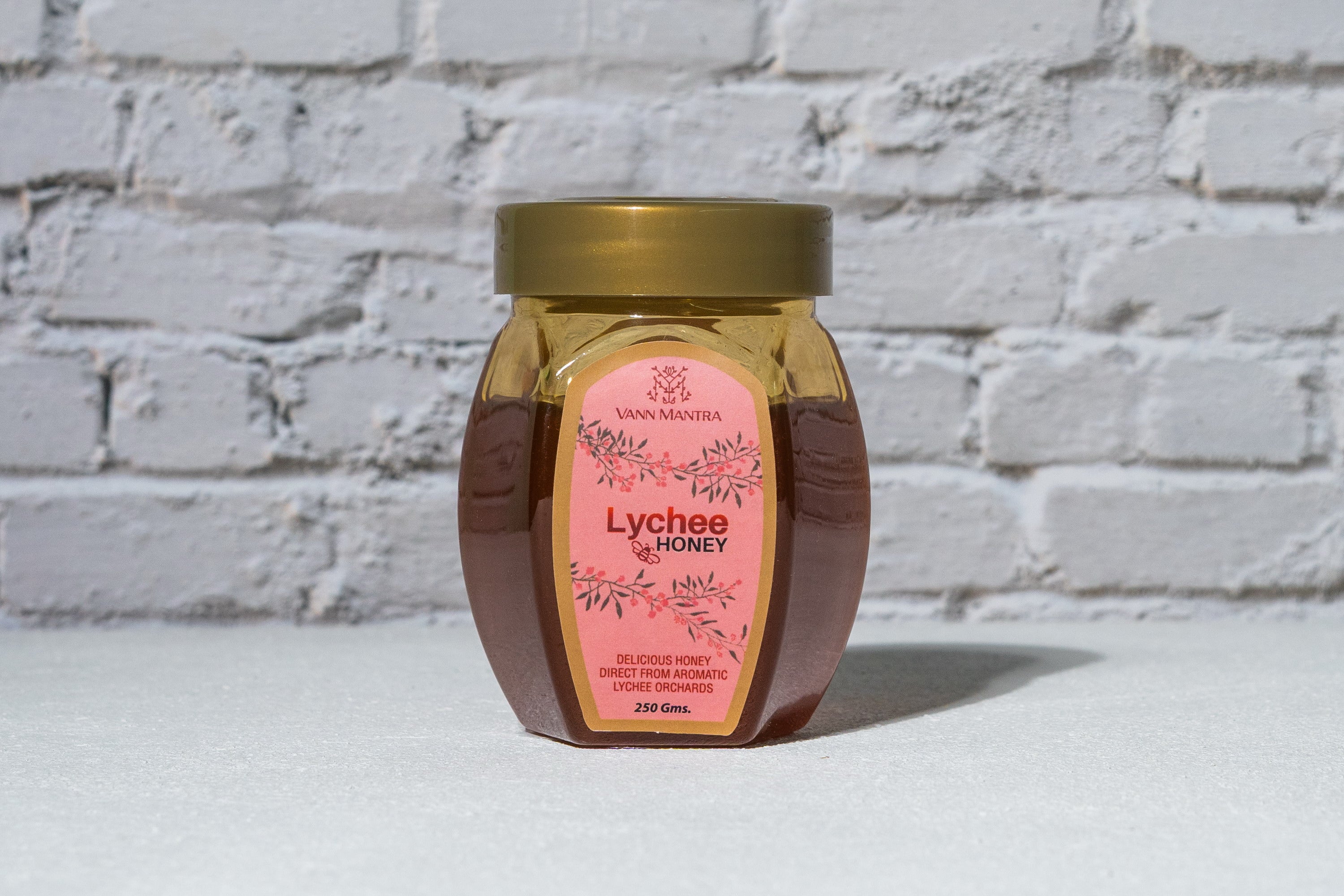 Jar of Lychee Honey in front of a brick wall 