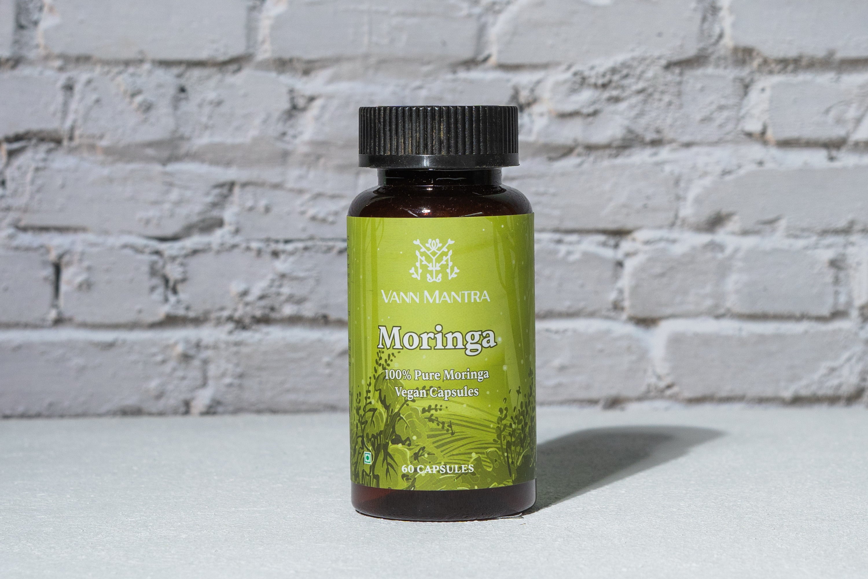 Moringa Capsules in front of a brick wall 
