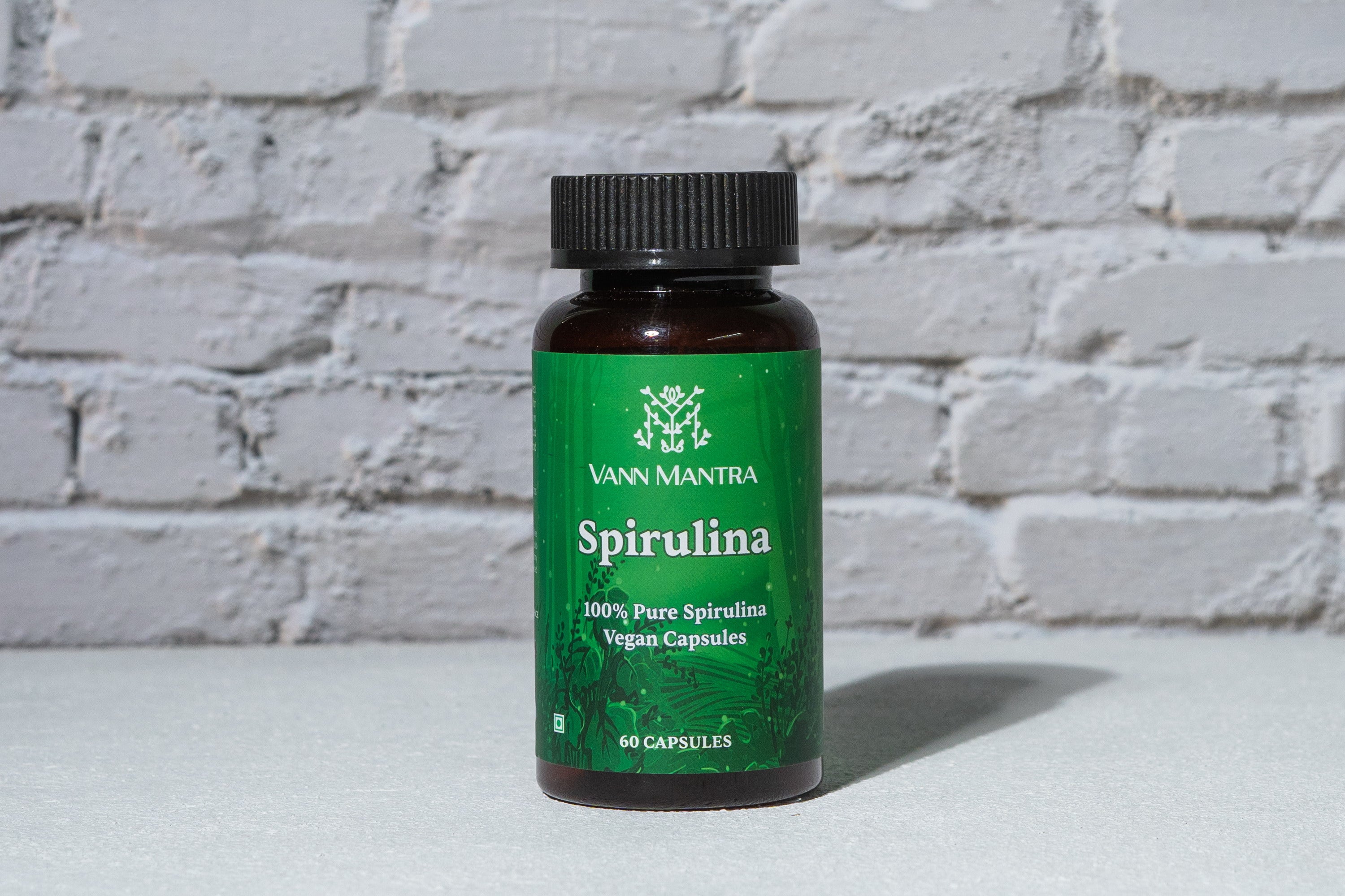 Spirulina Capsules in front of a brick wall 