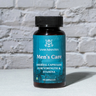 Men's Care Capsules in front of a brick wall 