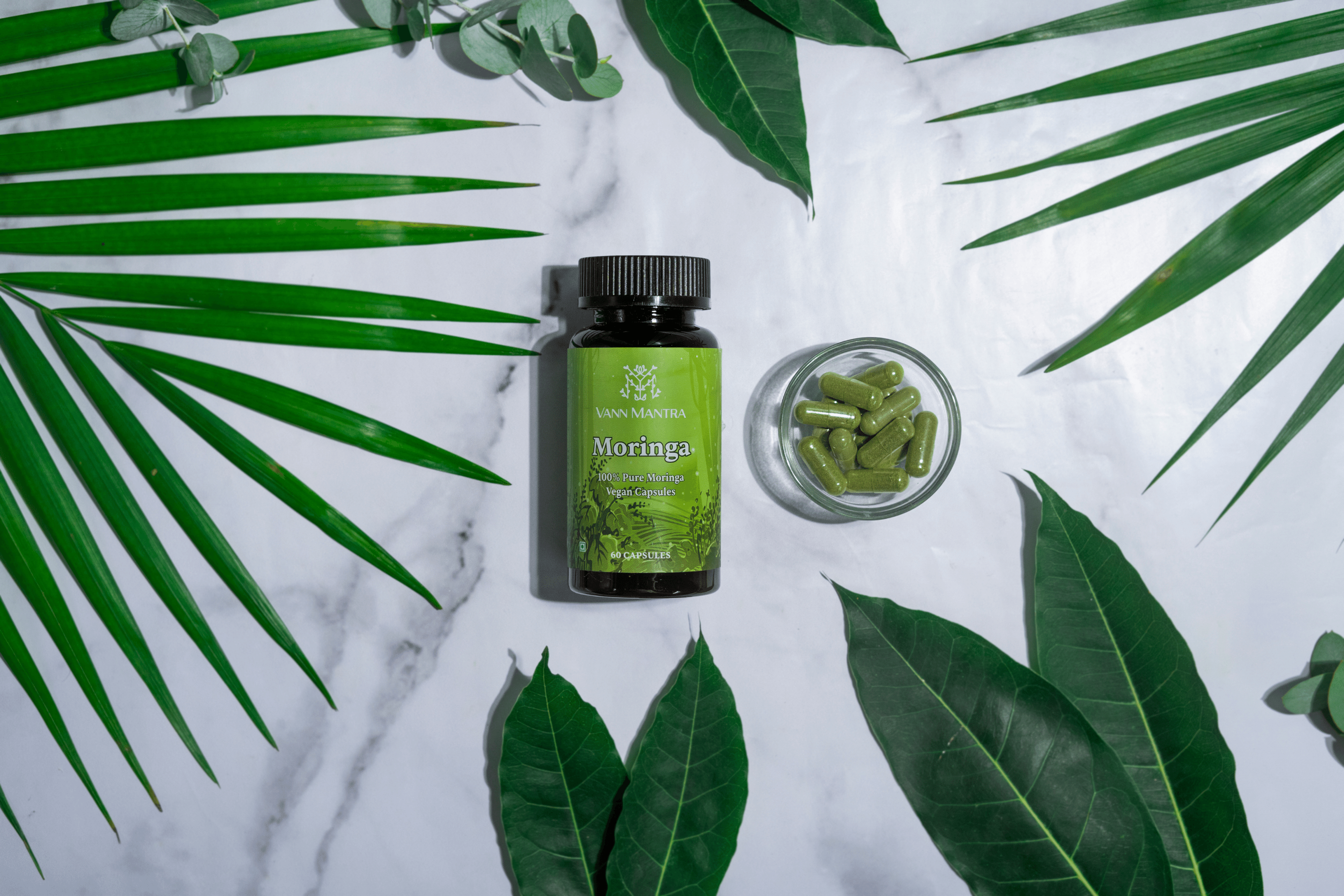 Moringa Capsules on a backdrop with plants. 