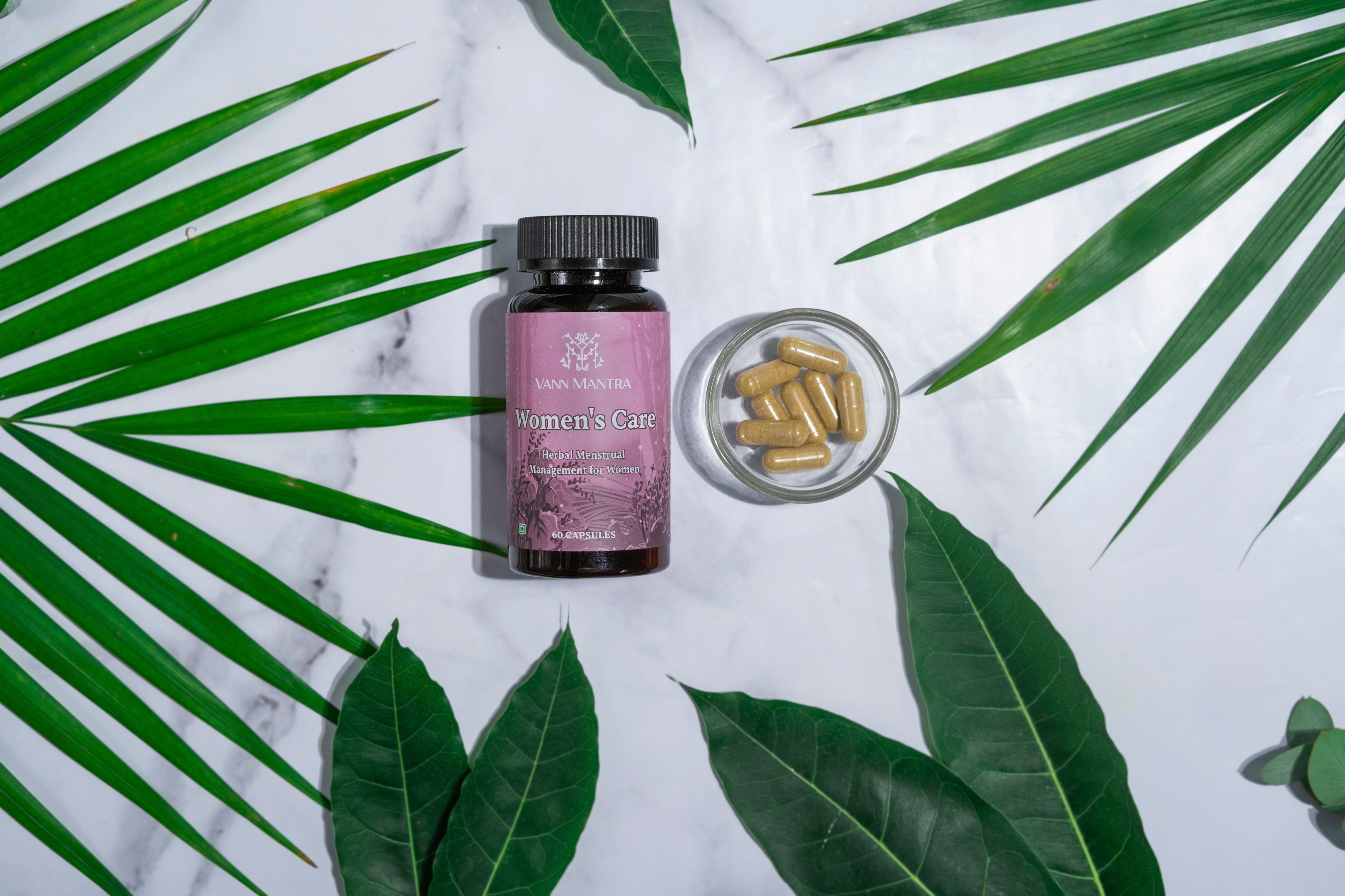 Women's Care Capsules on a backdrop with plants. 