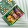 Box Of Satisfaction (Peachy Please, Berry Bliss, Lychee Honey) on a backdrop with plants