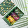 Box Of Flavor Surplus (Citrus Delight, Berry Bliss, Peachy Please) on a backdrop with plants
