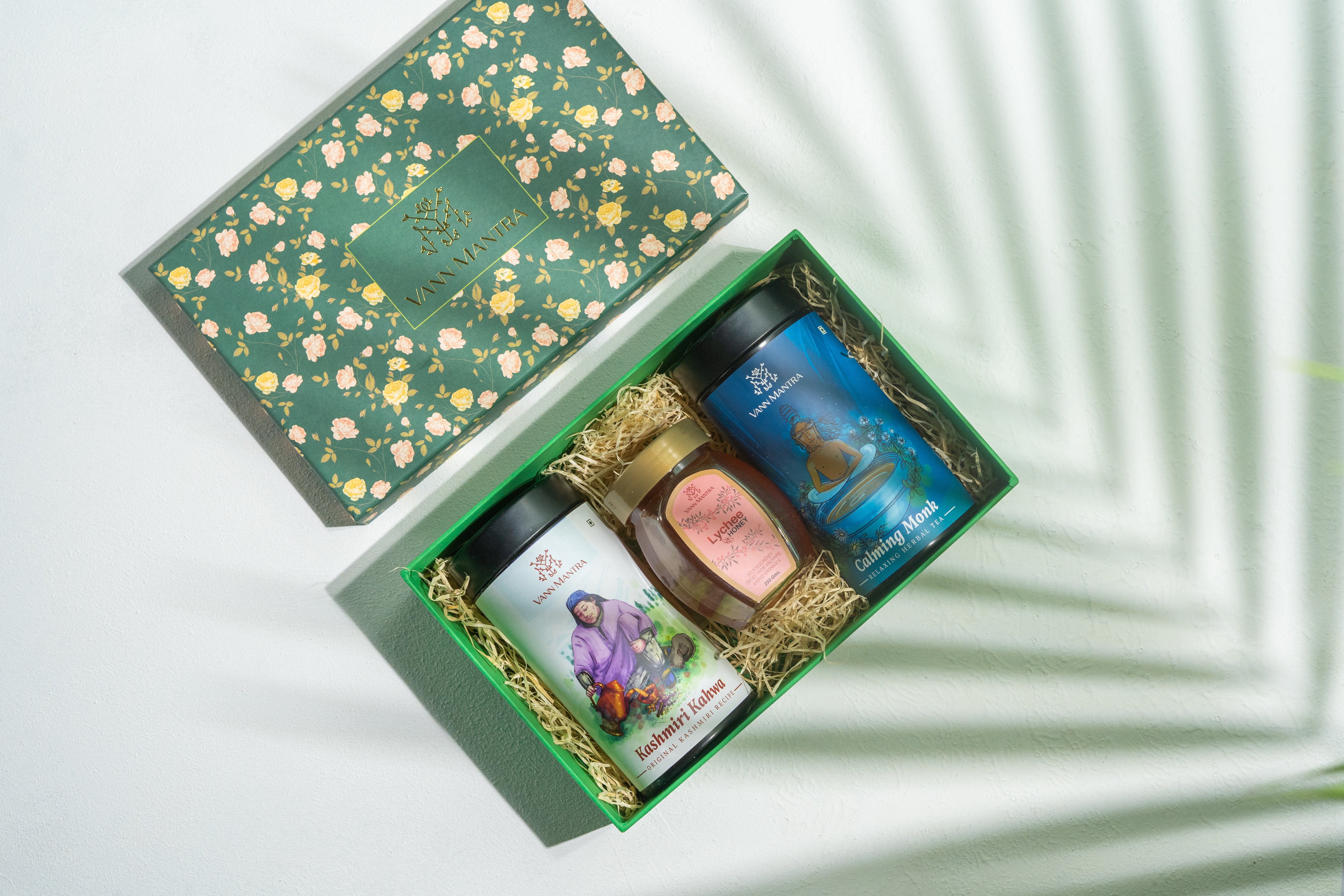 Box Of Serenity (Kashmiri Kahwa, Calming Monk, Lychee Honey) on a backdrop with plants