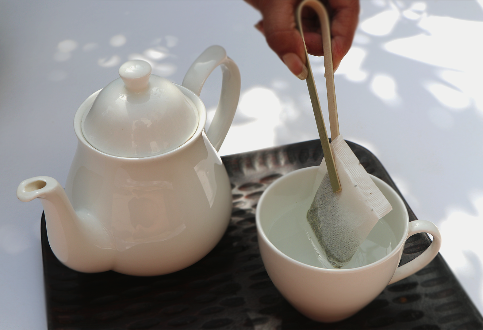 Teabag of Happy Belly- Daily Digestion Tea with a kettle on a tray. 