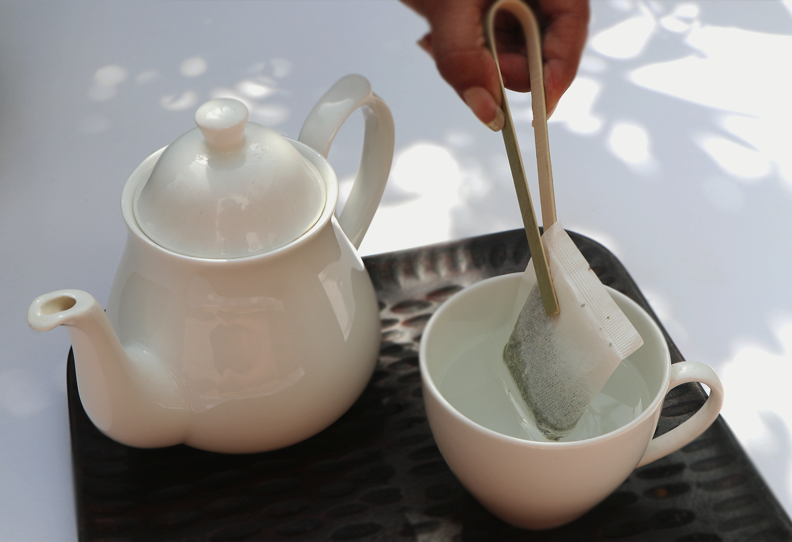 Teabag of Calming Monk Tea with a kettle on a tray. 